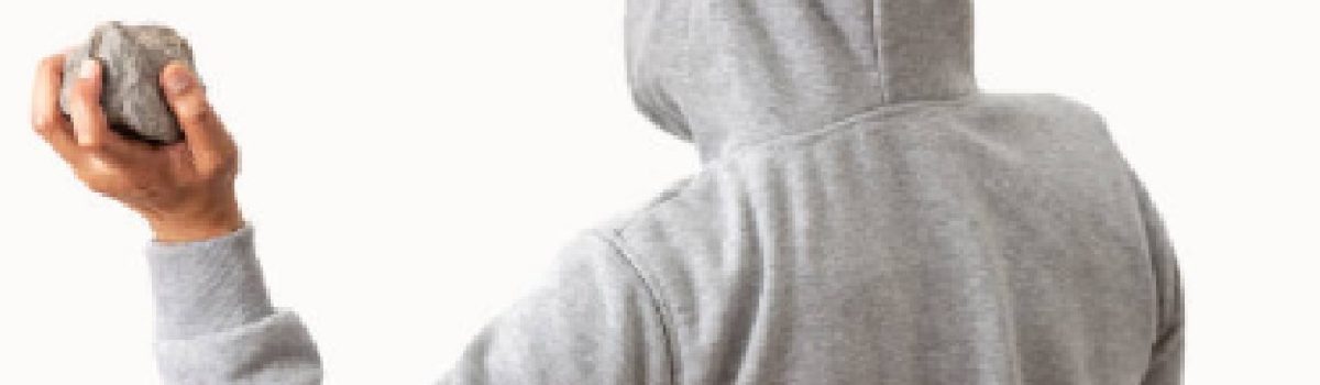 Rear view of a man holding a stone to throw it with white background