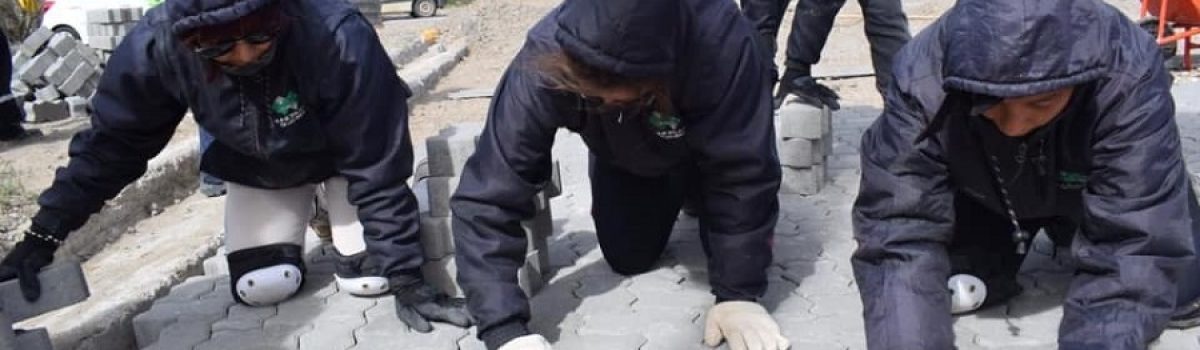 mujeres municipales adoquinando calles